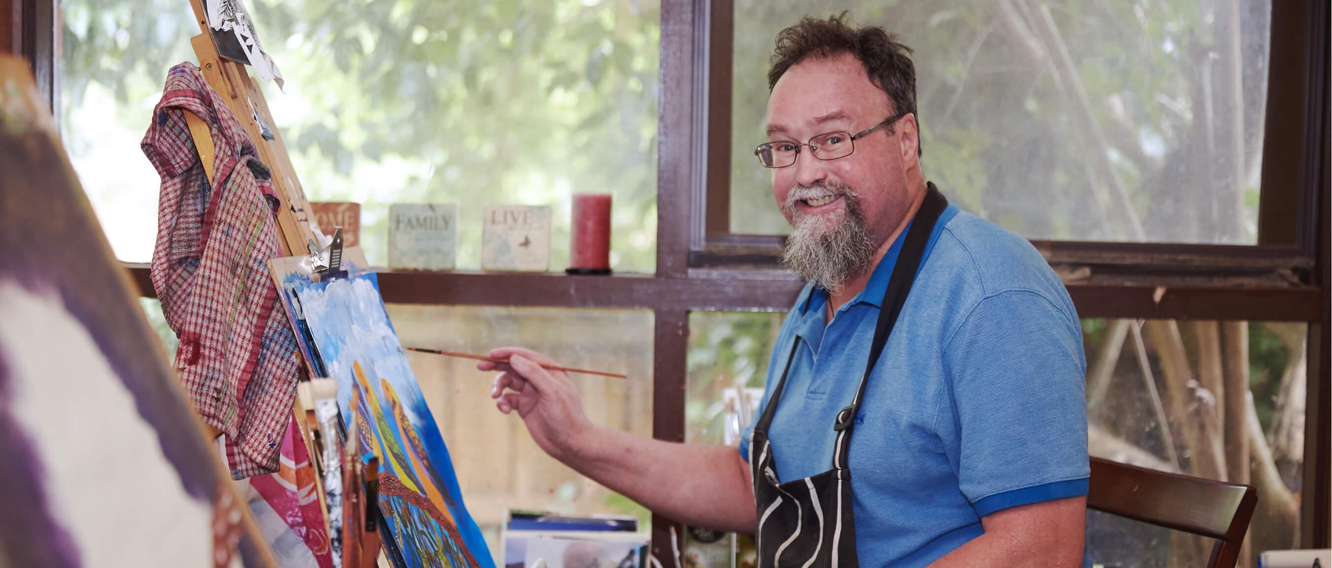 Nigel standing at his easel with a paintbrush in his hand